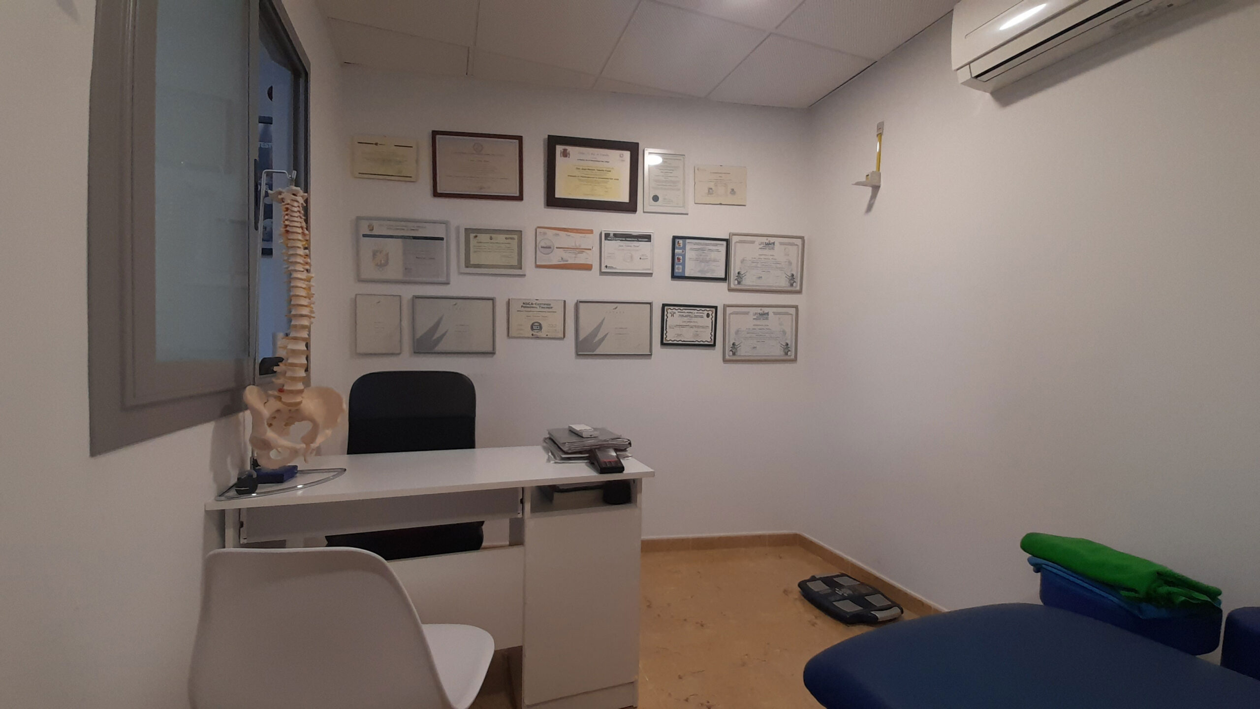 Despacho del fisioterapeuta con los títulos colgados en la pared